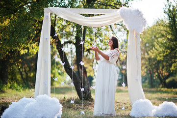 Happy pregnant woman on white dress background decoration arch o