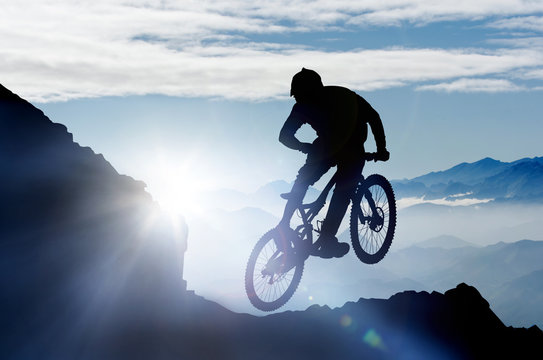Fototapete - springender Mountainbiker im Gebirge im Gegenlicht