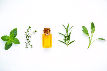 Bottle of essential oil with fresh herbal sage, rosemary, lemon