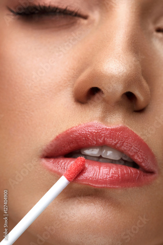 Leinwand Poster Beauty Makeup. Beautiful Woman Applies Lip Gloss