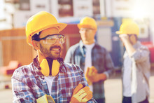Group Of Smiling Builders In Hardhats Outdoors