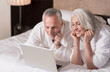 Smiling aged couple lying on the bed at home