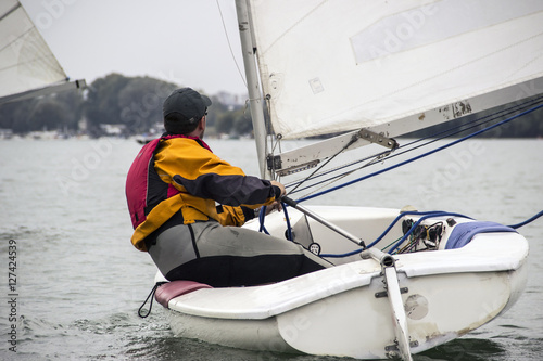 Fotografie, Obraz Man in the Finn-Class sailboat participates in one of the match race regattas on