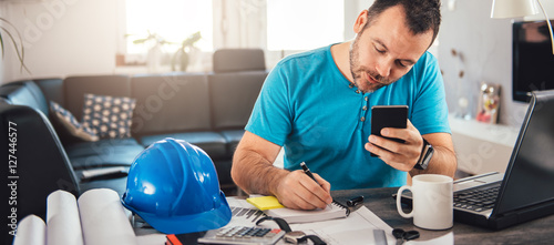 Fotomural Man writing notes and holding smart phone
