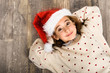 © javiindy - Adorable little girl wearing santa hat laying on wooden floor