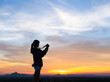 © max_play - Silhouette of woman shooting with camera at sunset