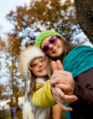 Two young sisters spending a nice time together in autumn day