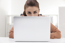 Woman In Brown Blouse Hiding Behind Her Laptop