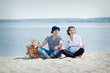 © 060808 - Man and pregnant woman sitting on the beach laugh and have fun, nautical style.