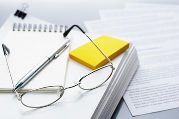 Poster - Checking and reviewing documents. Glasses, pen and pile of documents.
Pile of documents on gray reflection background.
