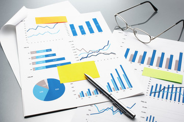 Poster - Reviewing financial reports. Graphs and charts.　Business reports, documents, glasses and pen. 
