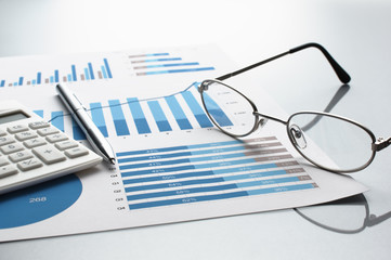 Poster - Reviewing business report. Graphs and charts.　Financial reports, documents, calculator, glasses and pen. 
