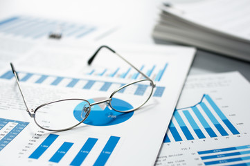 Poster - Checking business reports. Glasses and pile of documents.　Many graphs and charts. Pile of documents on gray reflection background.
