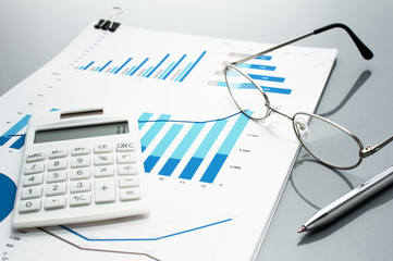 Poster - Reviewing business reports. Graphs and charts.　Financial reports, documents, calculator, glasses and pen. 
