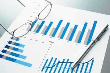 Poster - Blue charts, glasses and pen.　Business document on gray reflection background.
