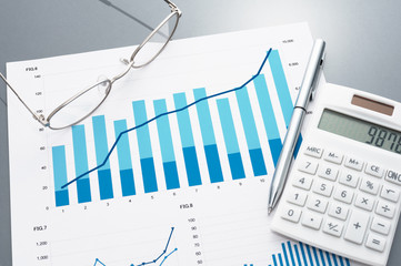 Poster - Financial report, calculator, glasses and pen. 
Reviewing business document. Graphs and charts.
