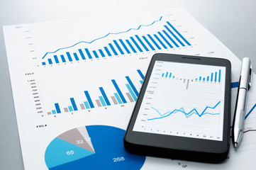 Poster - Business document, smart phone and pen on gray reflection background.
Many graphs and charts. Concept image of data gathering.
