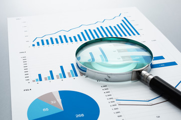 Poster - Business document and magnifying glass on gray reflection background.
Many graphs and charts. Concept image of data reviewing.
