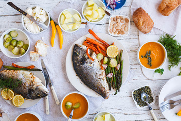 Family dinner table with baking fish and veggies.