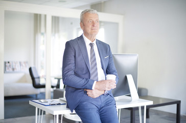 Wall Mural - Senior professional man portrait. Shot of a thoughtful senior businessman standing at office while on coffee break.