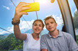 Young couple on mountain lift taking a selfie on a sunny day