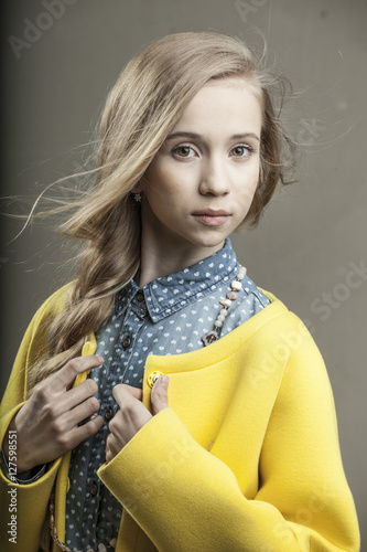 Beautiful Young Girl In Yellow Coat With Blonde Hair And Green
