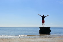 Young Man Standing On Rock At The Beach