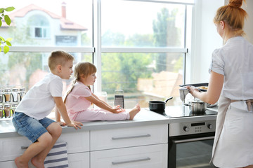 Young mother and kids tasting biscuits in kitchen