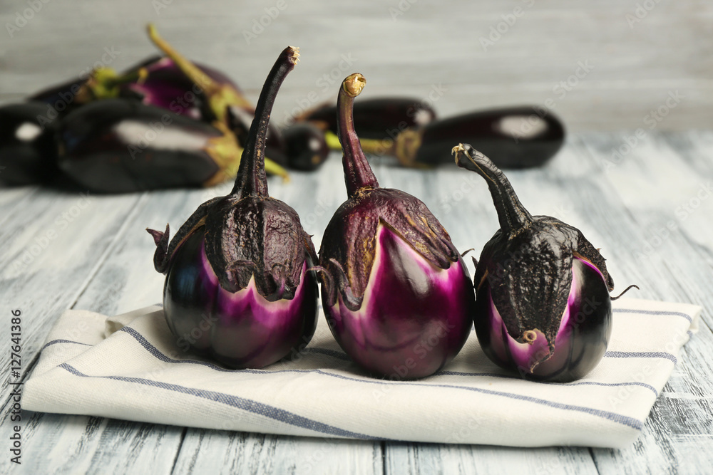 Composition with fresh eggplants and napkin on blurred gray background