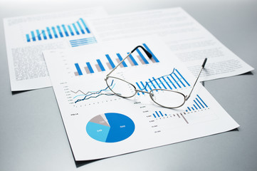 Poster - Checking business reports. Graphs and charts. Documents and glasses on gray reflection background.

