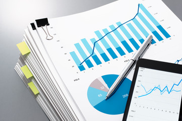 Poster - Pile of documents, smart phone and pen on gray reflection background.
Many graphs and charts. Concept image of data gathering.
