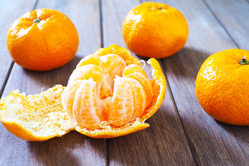 Close up of open tangerine with skin on a wooden table.