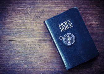 the compass over holy bible on wooden background with copy space