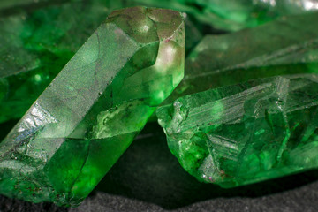 Closeup of a bunch of many green rough uncut emerald crystals