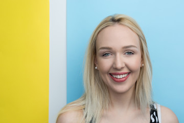 Young woman smiling with beautiful blond hair over color backgro