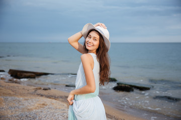 Wall Mural - Happy woman in hat walking on the beach