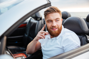 Young man talking on his phone and driving a car