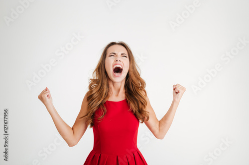 Fotografie, Obraz Mad furious young woman with raised hands standing and screaming