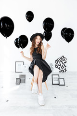 Poster - Happy attractive girl with black balloons and posters sitting