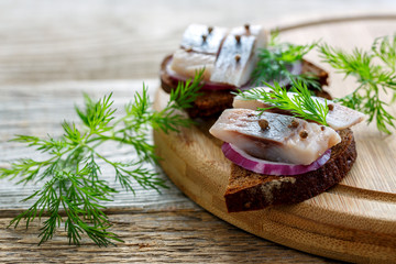 Sliced herring on rye bread with red onion.