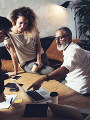 Team of coworkers making great work discussion in modern office.Young business teamwork concept.Bearded man talking with creative director and account manager.Vertical, blurred background.