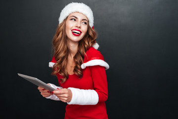 Poster - Laughing cheerful young woman holding tablet and looking away