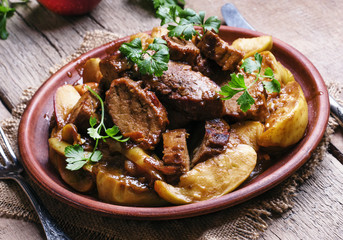 Wall Mural - Pork stew with apple sauce, vintage wooden background, selective