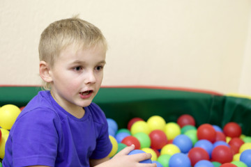 Wall Mural - Boy playing in box of balls