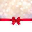 Christmas card - red ribbon / bow in front of a festive golden blurred lights bokeh background