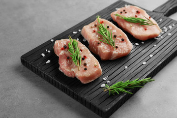 Wall Mural - Steaks in marinade on black wooden board and grey background