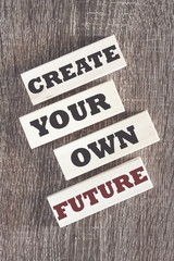 Create your own future. Motivational quote written on wooden tiles