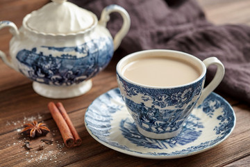 Masala tea chai latte homemade traditional hot Indian sweet milk with spices beverage in porcelain cup on wooden table background