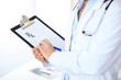 © rogerphoto - Close up of  female doctor  writing a medical prescription at clipboard while standing