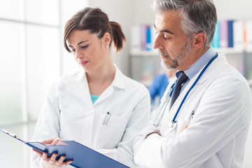 Wall Mural - Doctor checking medical records with his assistant